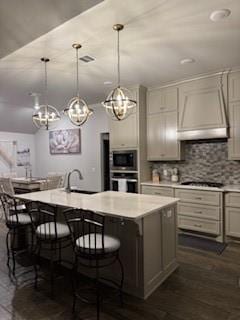 kitchen featuring light countertops, stainless steel oven, and a kitchen island with sink