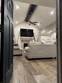 home theater room with vaulted ceiling with beams, a fireplace, and wood finished floors