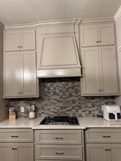 kitchen featuring custom exhaust hood, tasteful backsplash, stainless steel gas cooktop, and light countertops