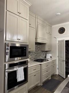 kitchen featuring tasteful backsplash, ornamental molding, appliances with stainless steel finishes, and custom exhaust hood