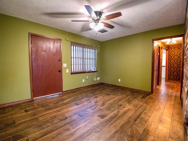 spare room featuring dark hardwood / wood-style floors, ceiling fan with notable chandelier, and a textured ceiling