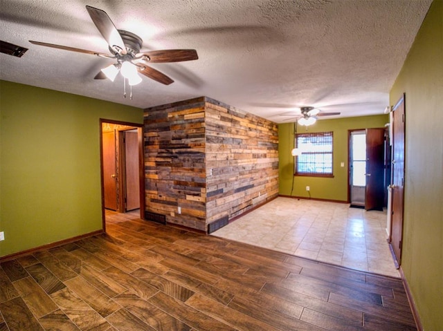 empty room with ceiling fan, wood-type flooring, and a textured ceiling