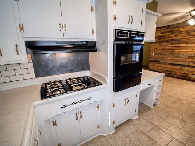 kitchen with black oven, ceiling fan, white cabinetry, gas stovetop, and wood walls