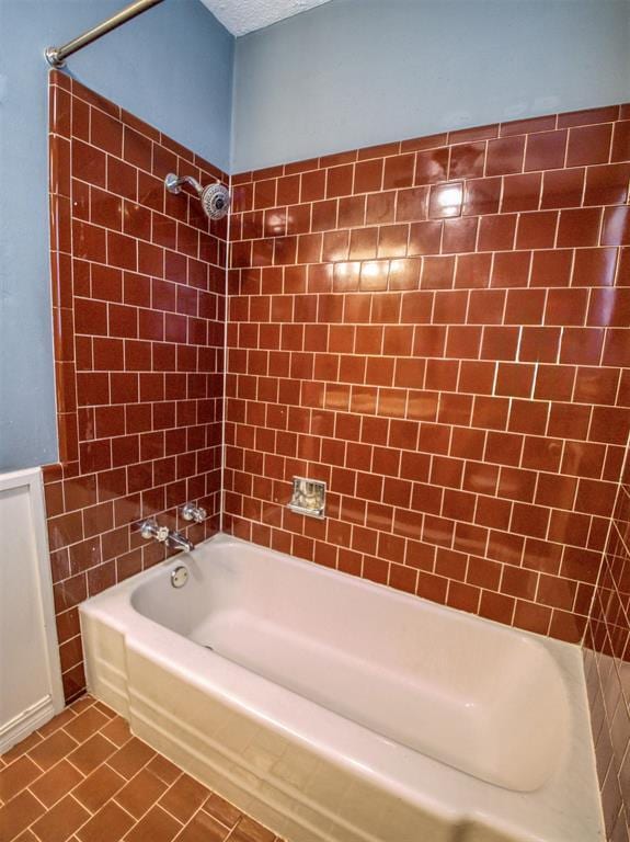 bathroom with a textured ceiling, tile patterned floors, and tiled shower / bath