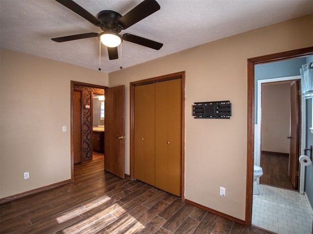 unfurnished bedroom with ceiling fan, ensuite bath, a textured ceiling, and a closet