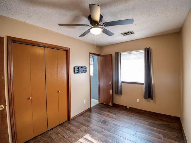 unfurnished bedroom featuring ceiling fan, a textured ceiling, dark hardwood / wood-style flooring, and a closet