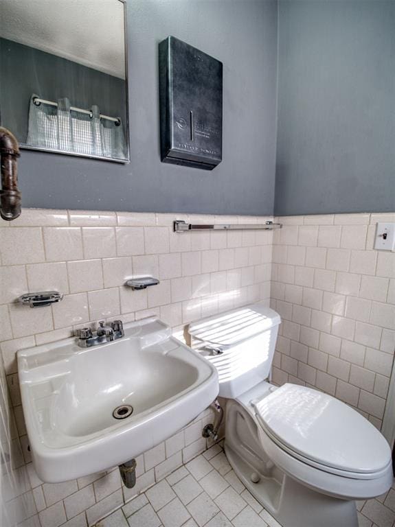 bathroom featuring tile patterned flooring, sink, tile walls, and toilet