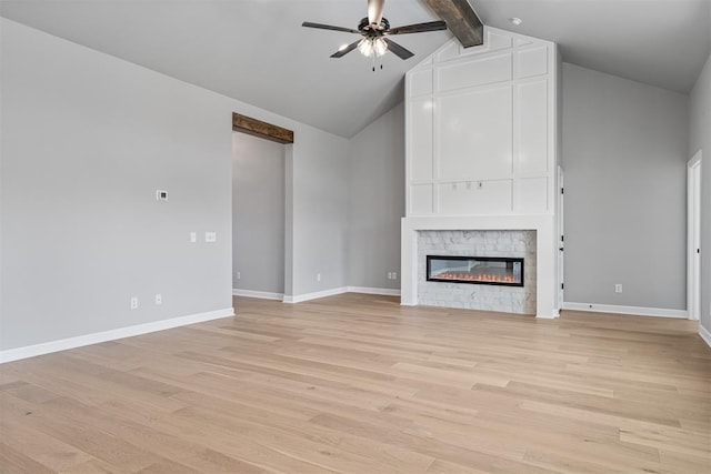 unfurnished living room featuring light wood-style floors, ceiling fan, a fireplace, and beamed ceiling