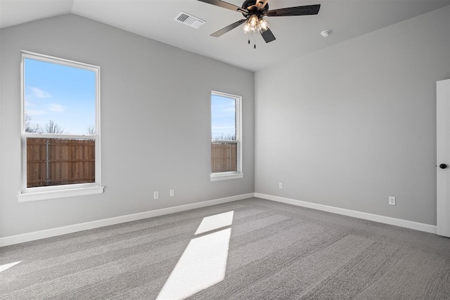 spare room featuring carpet floors, visible vents, a ceiling fan, vaulted ceiling, and baseboards