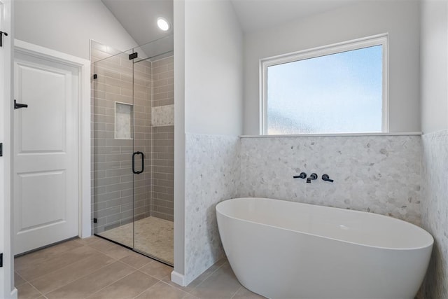 full bathroom featuring a stall shower, a wainscoted wall, tile patterned floors, a freestanding bath, and tile walls