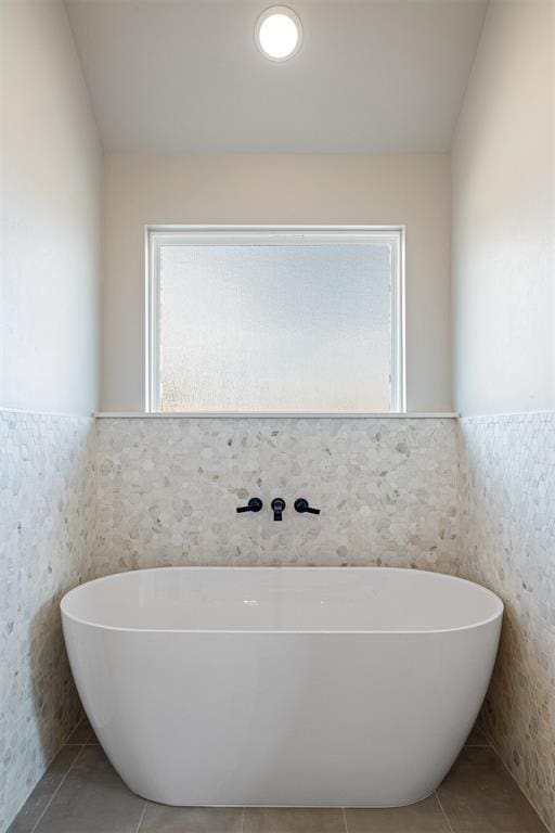 full bathroom featuring tile patterned flooring, a soaking tub, and wainscoting