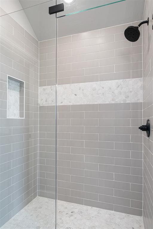 full bath featuring lofted ceiling and a tile shower