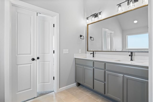 full bath featuring double vanity, tile patterned flooring, baseboards, and a sink