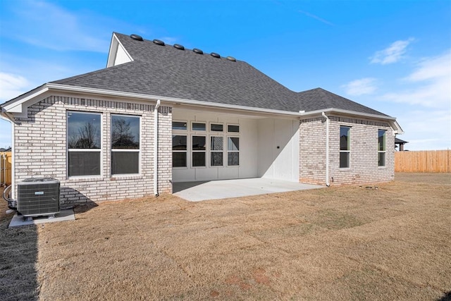 back of house with driveway, central AC unit, a shingled roof, and brick siding