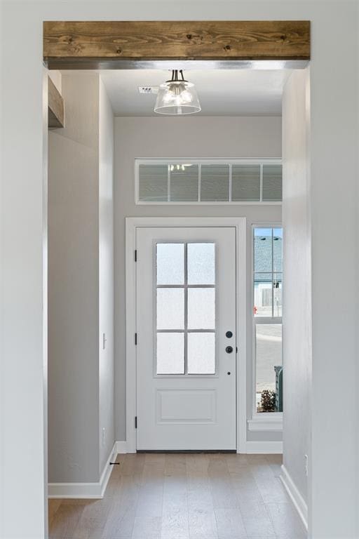 doorway with beam ceiling and baseboards