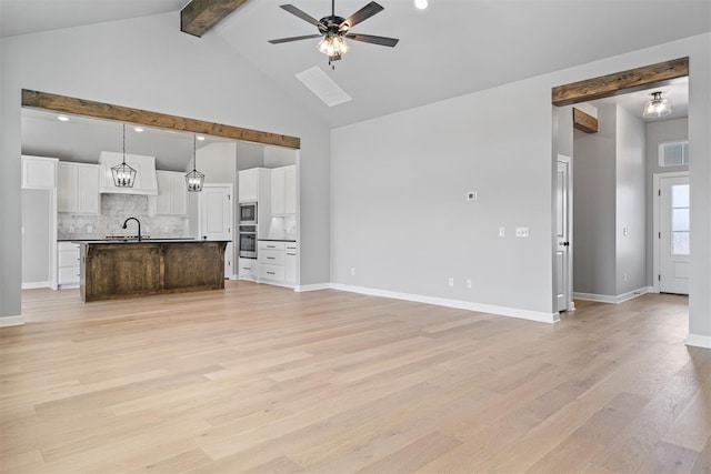 unfurnished living room with high vaulted ceiling, a ceiling fan, baseboards, light wood finished floors, and beamed ceiling