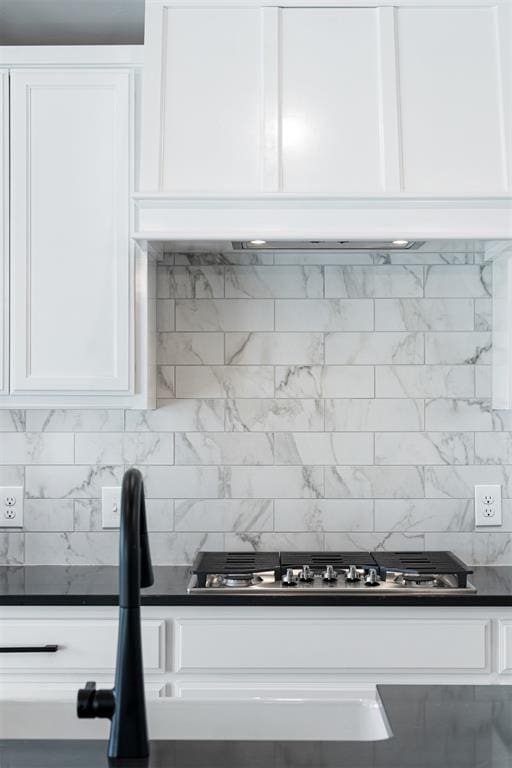 interior details featuring dark countertops, white cabinets, backsplash, and ventilation hood