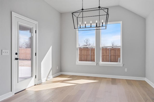 unfurnished dining area with light wood-style floors, lofted ceiling, and baseboards