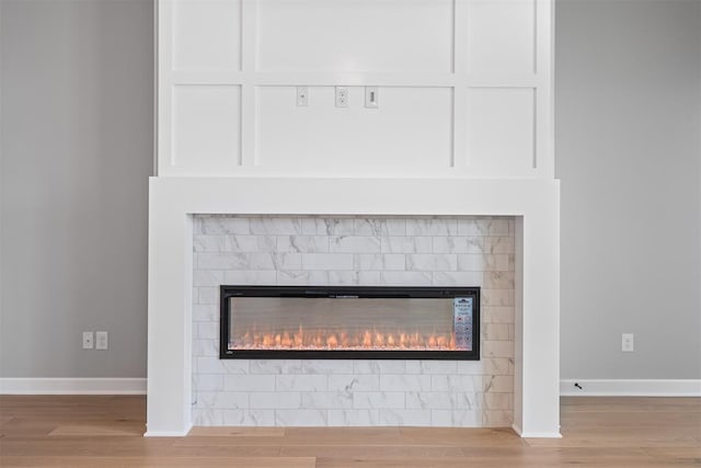 details featuring baseboards, wood finished floors, and a glass covered fireplace