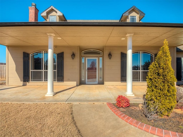 view of exterior entry featuring a chimney and a porch