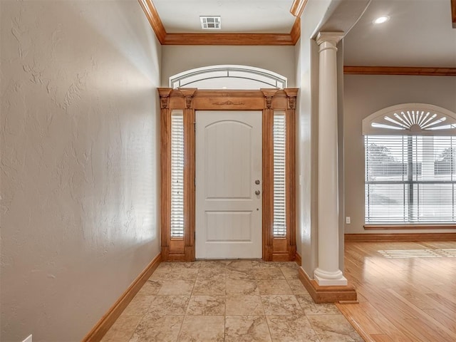 entryway featuring crown molding, visible vents, decorative columns, and baseboards