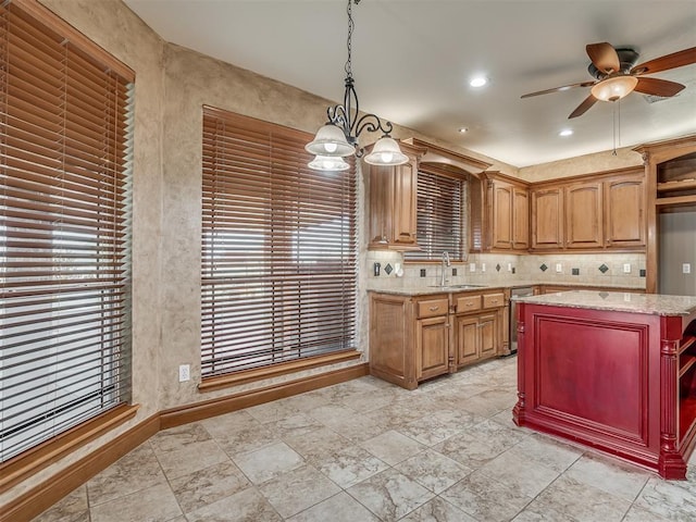 kitchen featuring light stone counters, a center island, sink, and hanging light fixtures