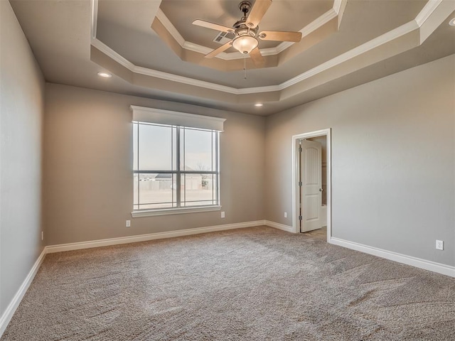 empty room with crown molding, ceiling fan, a raised ceiling, and carpet floors