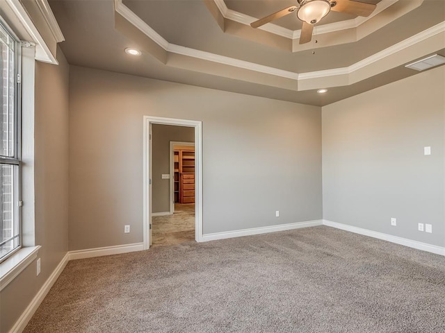 carpeted empty room featuring crown molding, ceiling fan, and a tray ceiling