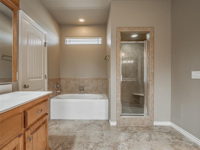 full bathroom featuring a garden tub, a shower stall, baseboards, and vanity