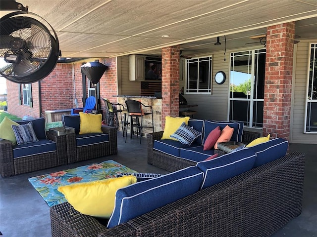 view of patio / terrace with a bar, outdoor lounge area, and ceiling fan