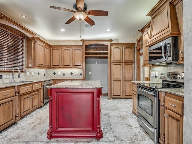 kitchen with light stone counters, sink, a center island, and appliances with stainless steel finishes