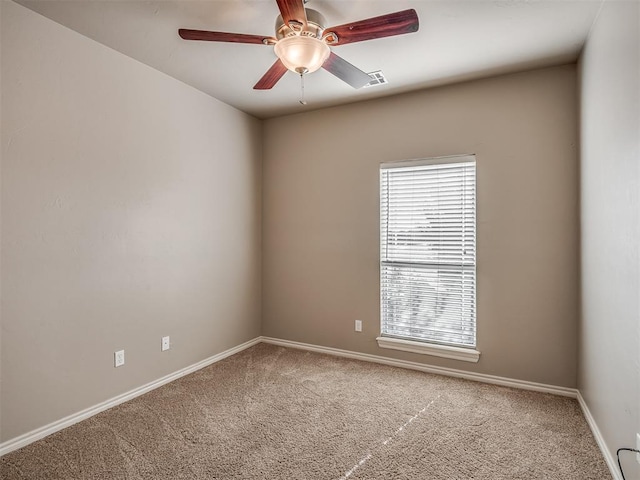 carpeted spare room featuring visible vents, baseboards, and a ceiling fan