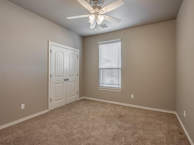 carpeted spare room with visible vents, ceiling fan, and baseboards