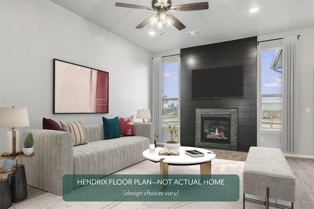 living room featuring a fireplace, light hardwood / wood-style floors, and ceiling fan