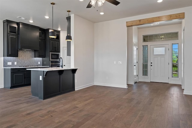 13325 SW 8th St, Yukon, OK 73099 - kitchen featuring decorative backsplash, a breakfast bar, light countertops, dark cabinetry, and stainless steel appliances