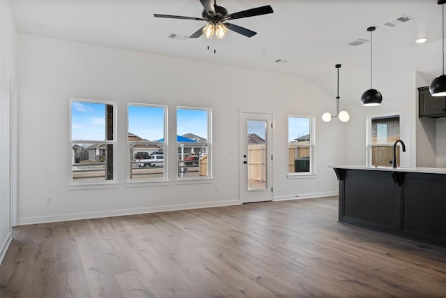 unfurnished living room with vaulted ceiling, visible vents, and wood finished floors