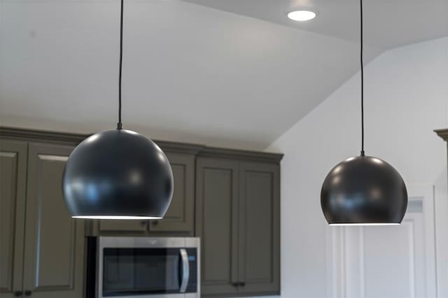 interior details featuring stainless steel microwave, gray cabinetry, and hanging light fixtures