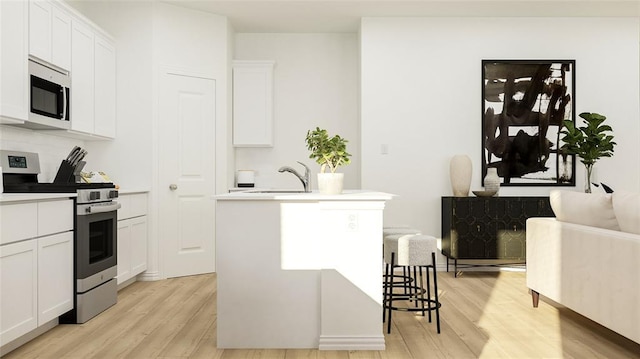 kitchen with stainless steel appliances, an island with sink, a breakfast bar area, and white cabinets