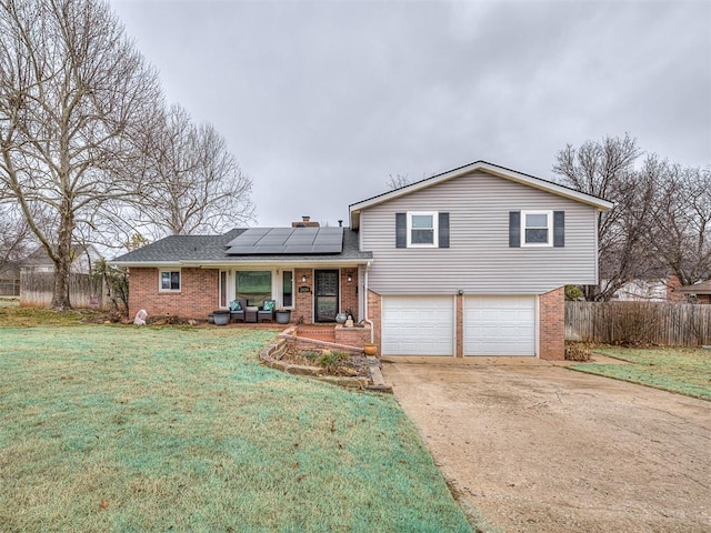 tri-level home with a garage, a front lawn, covered porch, and solar panels