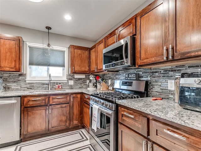 kitchen with light stone countertops, appliances with stainless steel finishes, sink, and decorative backsplash