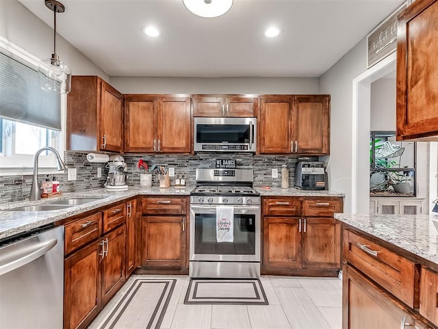 kitchen with appliances with stainless steel finishes, sink, decorative backsplash, hanging light fixtures, and light stone counters