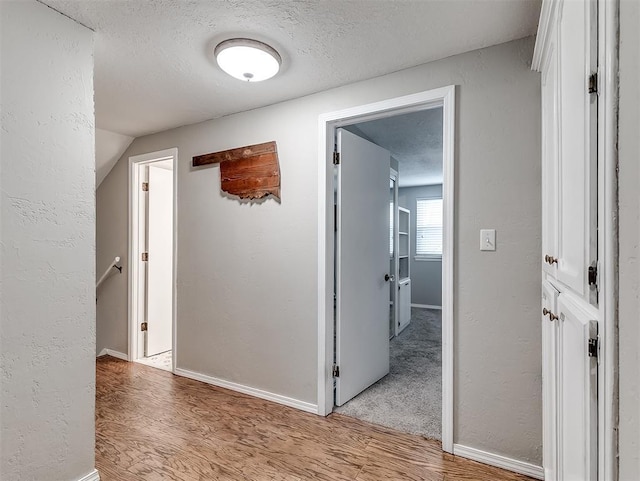 hall featuring a textured ceiling and light hardwood / wood-style floors