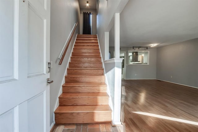 stairs featuring track lighting and hardwood / wood-style floors