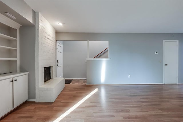 unfurnished living room with a brick fireplace and light hardwood / wood-style floors