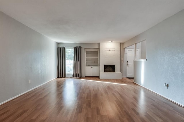 unfurnished living room with a brick fireplace and light hardwood / wood-style floors