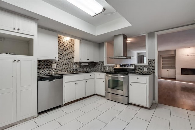 kitchen featuring stainless steel appliances, exhaust hood, white cabinets, and decorative backsplash