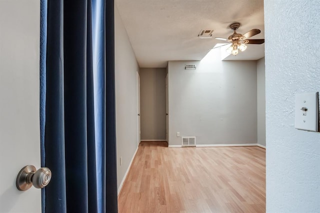 empty room with ceiling fan and light hardwood / wood-style flooring