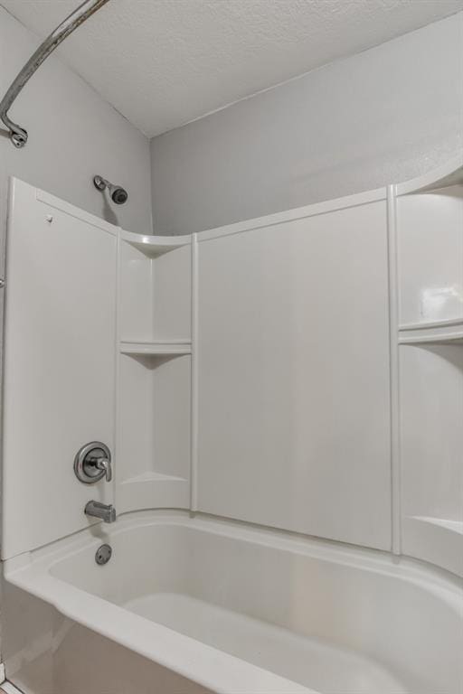 bathroom featuring bathtub / shower combination and a textured ceiling