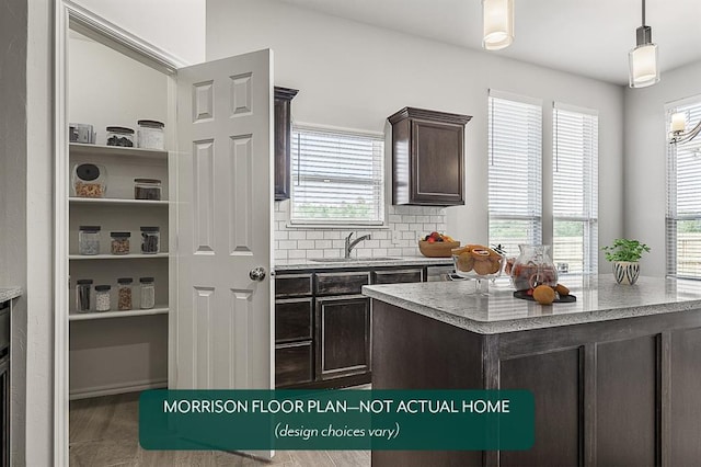 kitchen with hanging light fixtures, sink, a wealth of natural light, and dark brown cabinetry