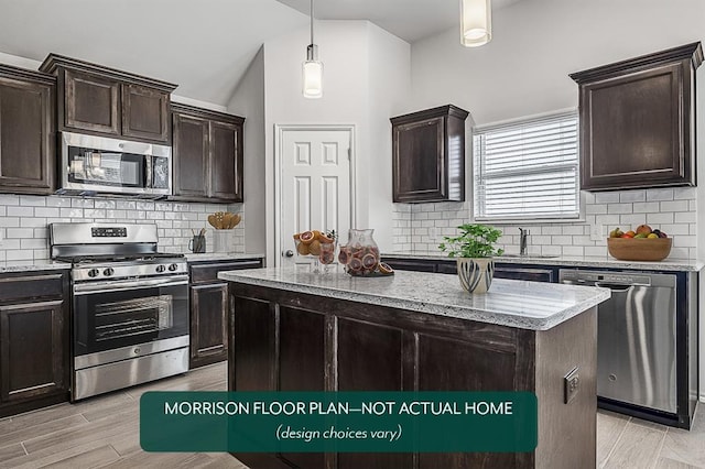 kitchen featuring dark brown cabinetry, lofted ceiling, decorative light fixtures, appliances with stainless steel finishes, and a kitchen island